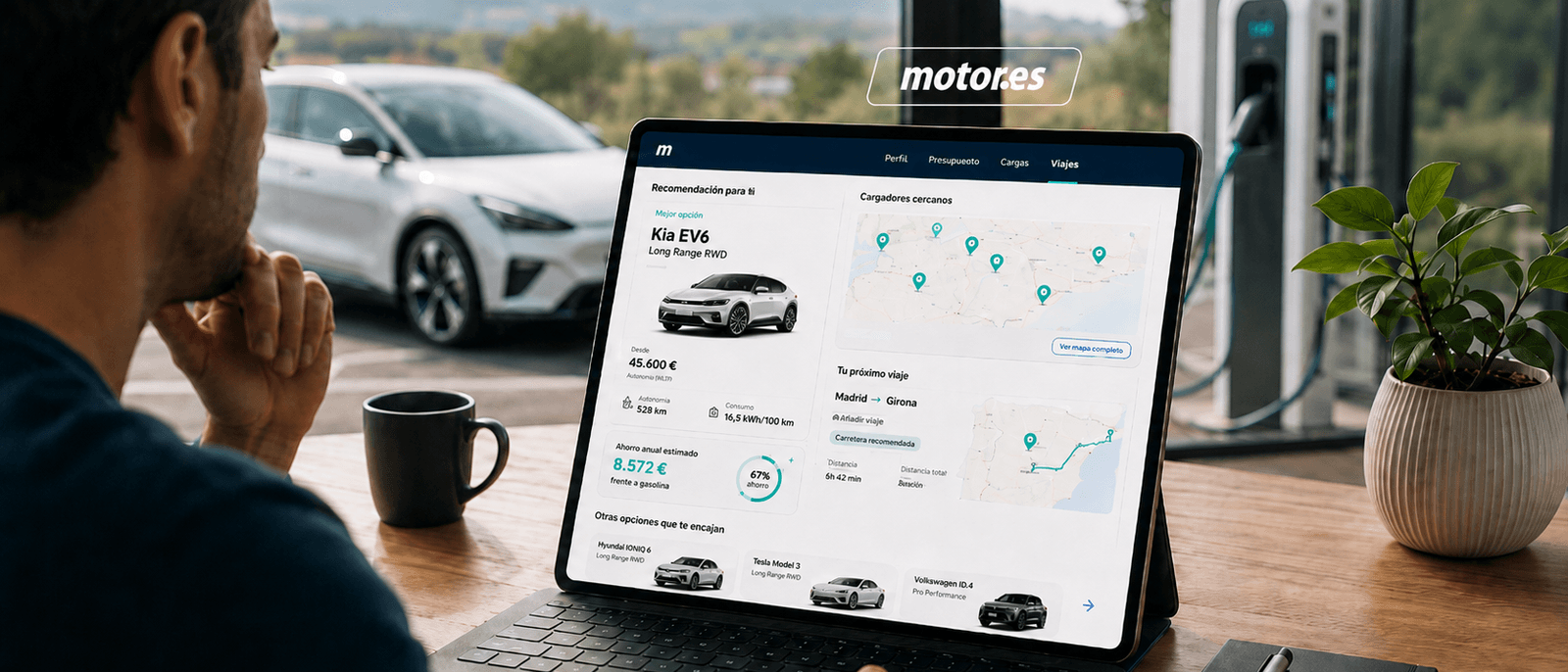 Persona usando un portátil sobre escritorio de madera con la integración QuantumDrive en Motor.es visible — recomendación de Kia EV6, ahorro anual, mapa de cargadores cercanos y próximo viaje Madrid-Girona
